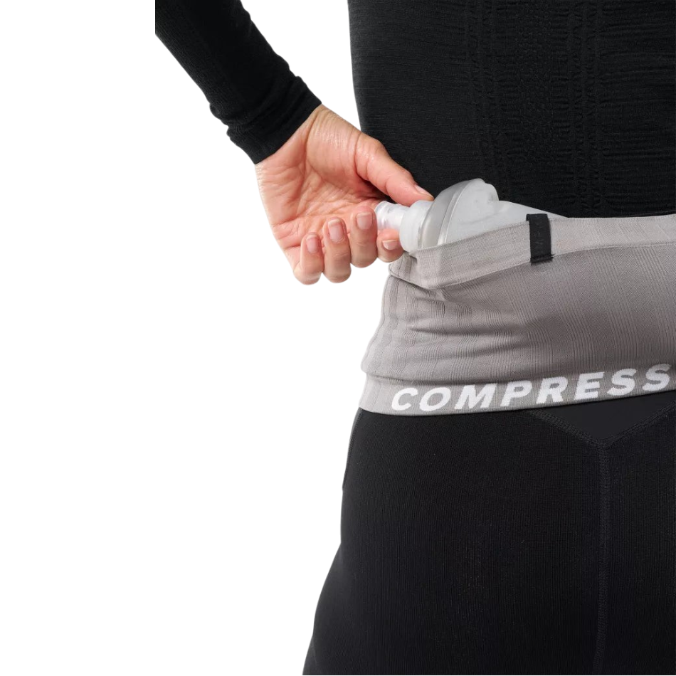 Up & Running Compressport Free Belt 2.0 in grey worn around the waist with a soft flask being inserted into the pocket