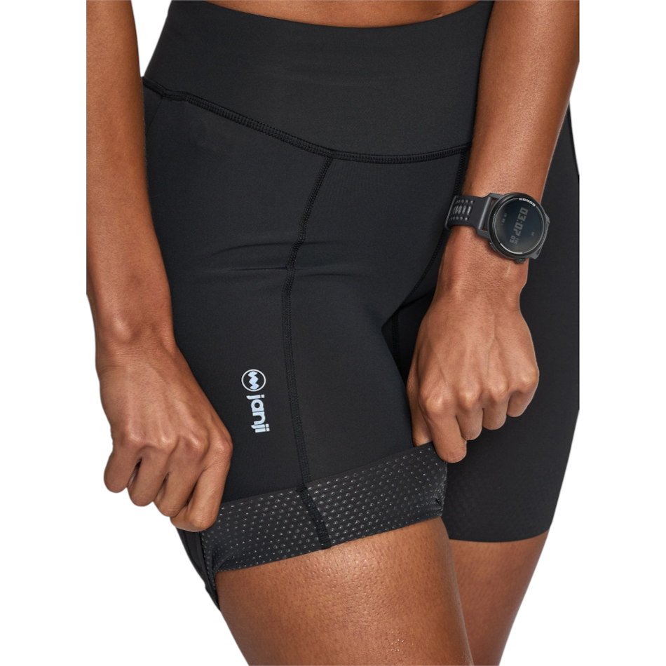 Up & Running Janji women's 7-inch black Pace running shorts with a textured hem and reflective logo detail.